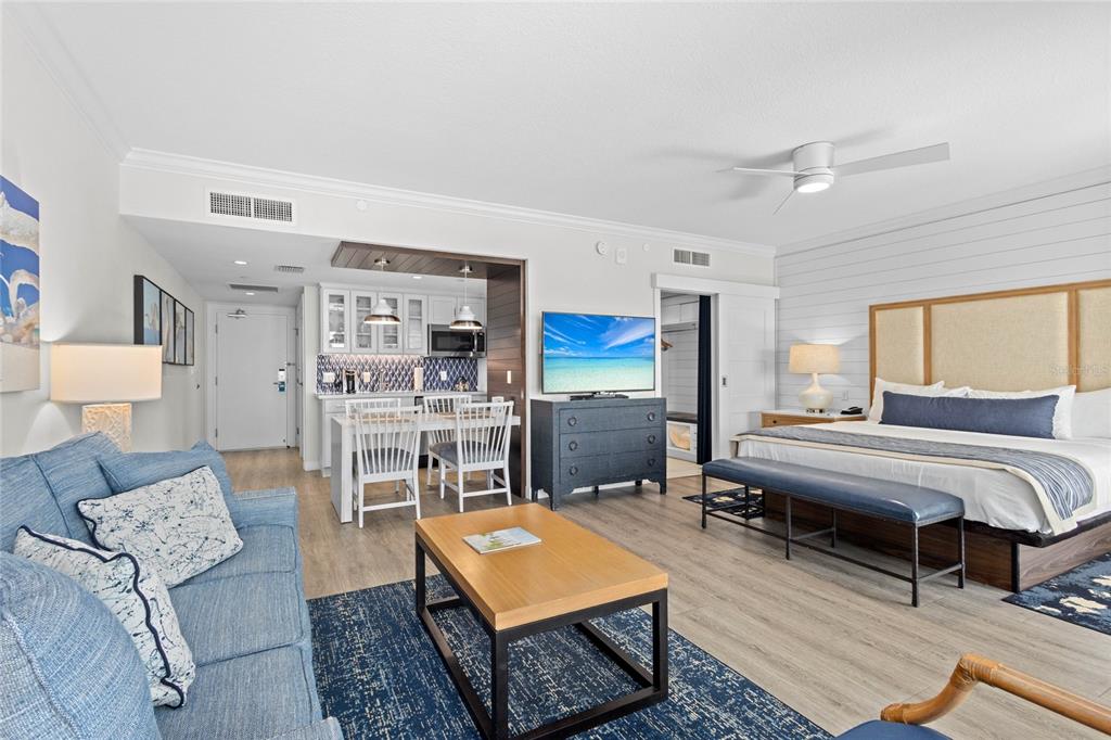 A studio hotel room features a blue sofa, a dining area, and a king bed — 250 SANDS POINT ROAD UNIT 5106, LONGBOAT KEY, FL