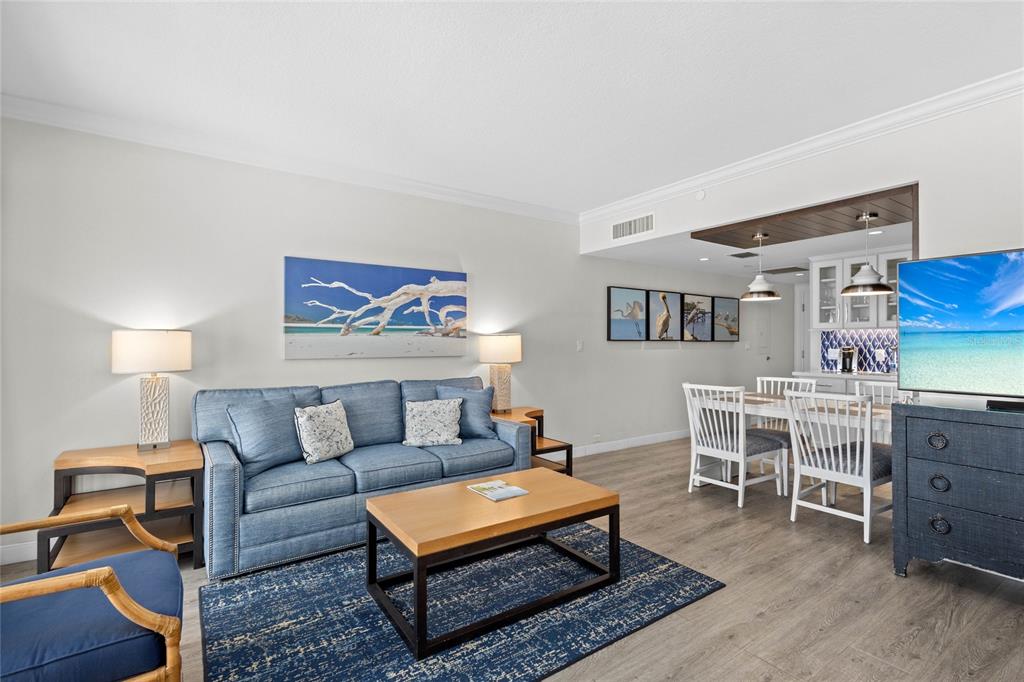 A living room with a blue sofa, coffee table, and an adjacent dining area — 250 SANDS POINT ROAD UNIT 5106, LONGBOAT KEY, FL