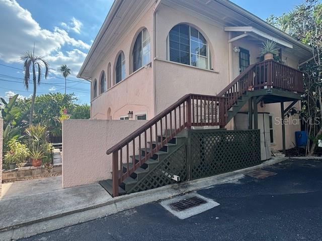 A two-story pink stucco building features an exterior wooden staircase leading to an upper deck — 1604 N OSCEOLA AVENUE, CLEARWATER, FL