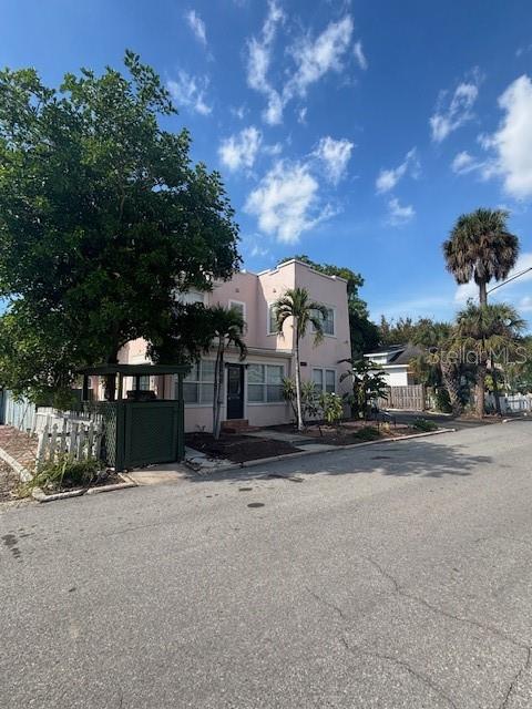 A two-story light pink house with a green fenced patio sits beside a large tree — 1604 N OSCEOLA AVENUE, CLEARWATER, FL