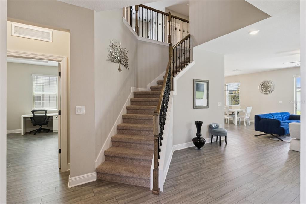 An interior view shows a carpeted staircase with a metal railing next to a living area — 7745 SOMERSWORTH DRIVE, KISSIMMEE, FL