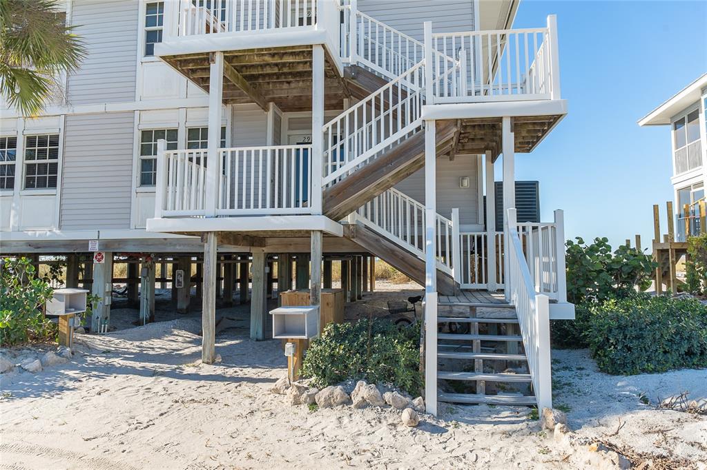 An elevated beach house with wooden stairs leading to a deck and sandy ground — 7466 PALM ISLAND DRIVE UNIT 2911, PLACIDA, FL