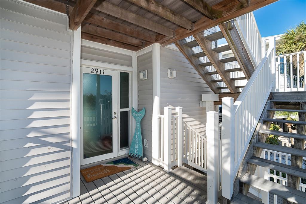 An exterior view of a beach house entrance with a wooden staircase and welcome sign — 7466 PALM ISLAND DRIVE UNIT 2911, PLACIDA, FL