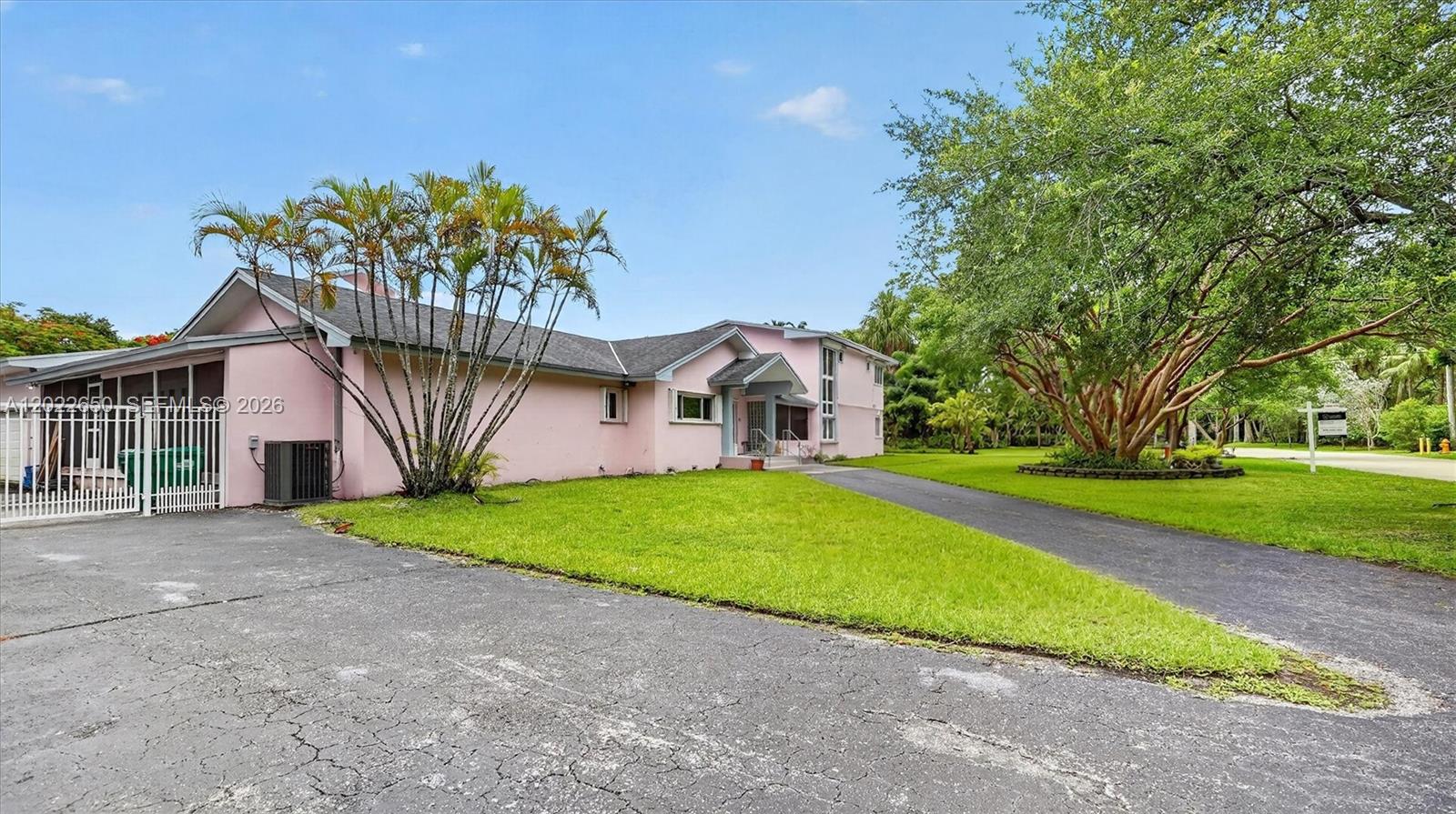 A pink, single-story house with a paved driveway and large trees on a grassy lot — 11651 SW 64th Ave, Pinecrest FL 33156, PINECREST, FL