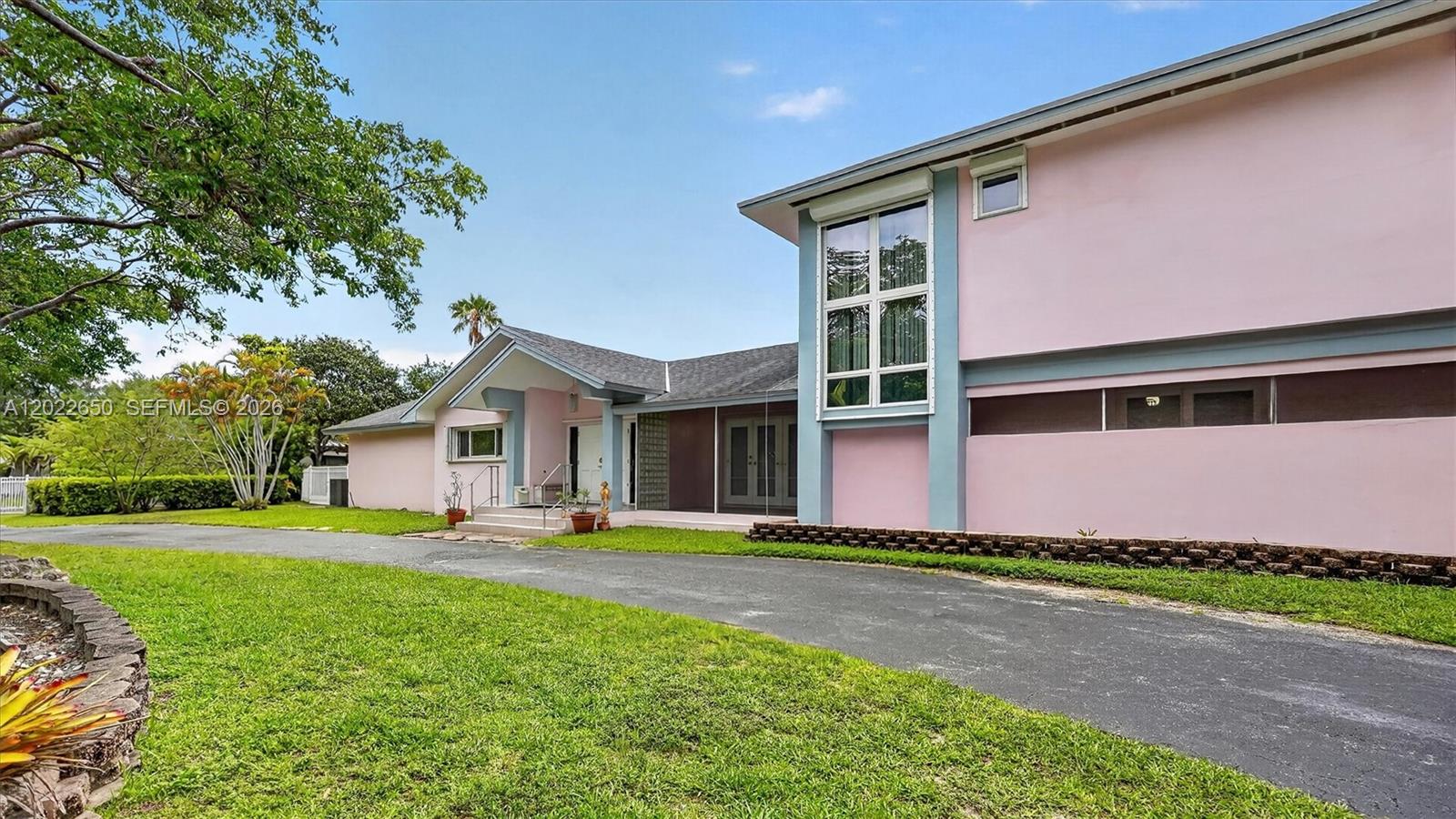 A pink two-story house features a paved driveway, a screened porch, and large windows — 11651 SW 64th Ave, Pinecrest FL 33156, PINECREST, FL