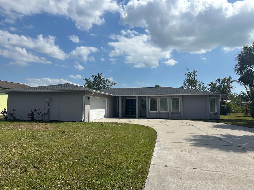 A single-story gray house with a white garage door and a concrete driveway — 230 ANNAPOLIS LANE, ROTONDA WEST, FL