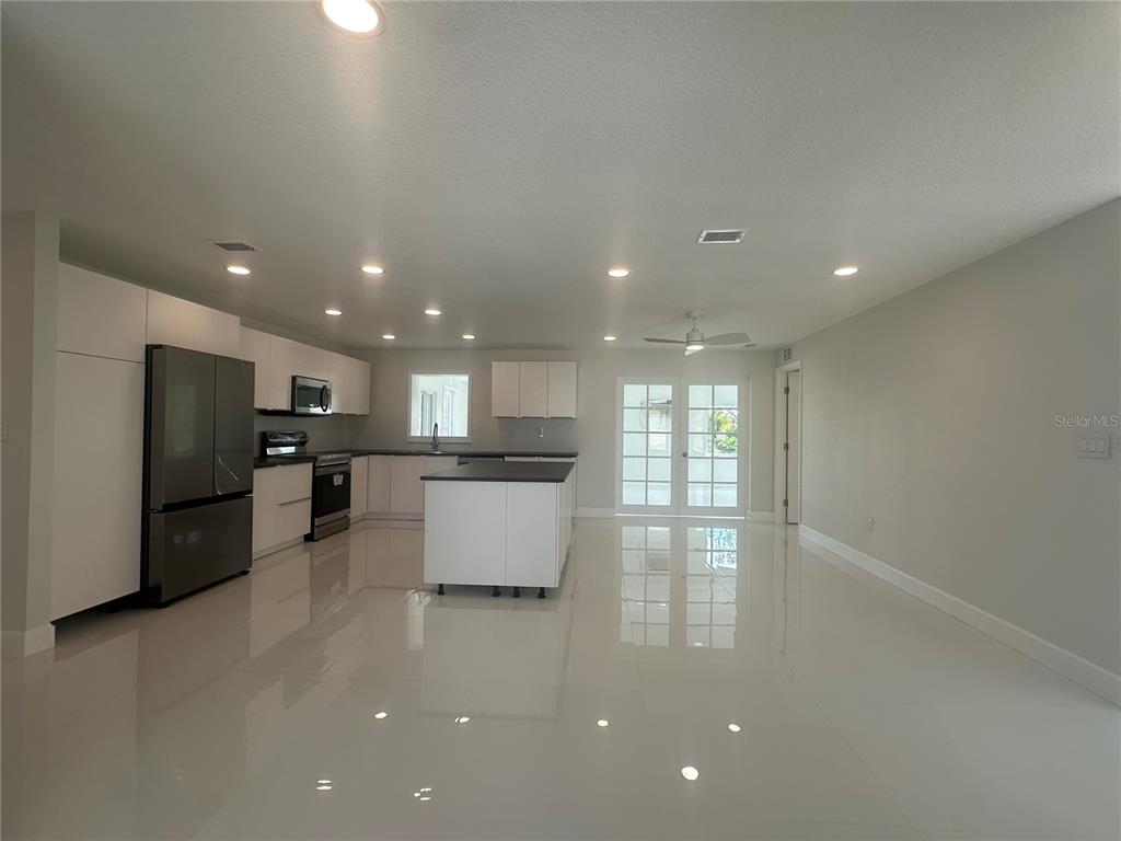 A modern kitchen features white cabinets, a central island, stainless steel appliances, and tile flooring — 230 ANNAPOLIS LANE, ROTONDA WEST, FL