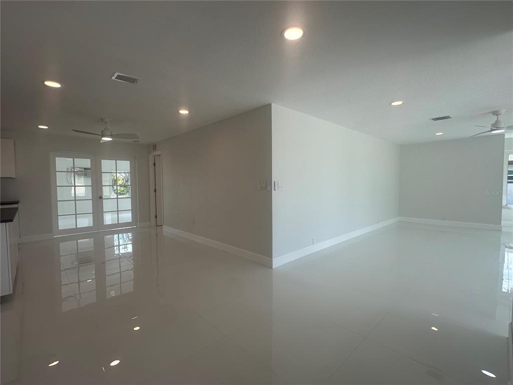 An open-concept room features white tile flooring, recessed lighting, and a set of French doors — 230 ANNAPOLIS LANE, ROTONDA WEST, FL