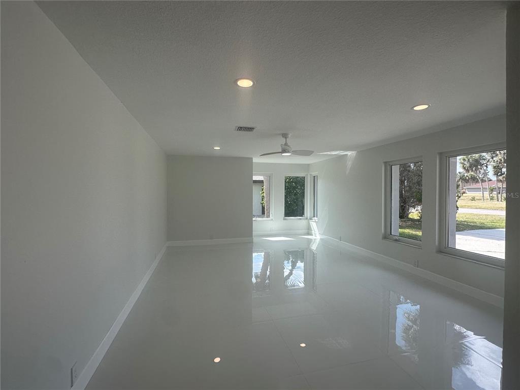 An empty room with white walls, glossy tile flooring, recessed lighting, and large windows — 230 ANNAPOLIS LANE, ROTONDA WEST, FL