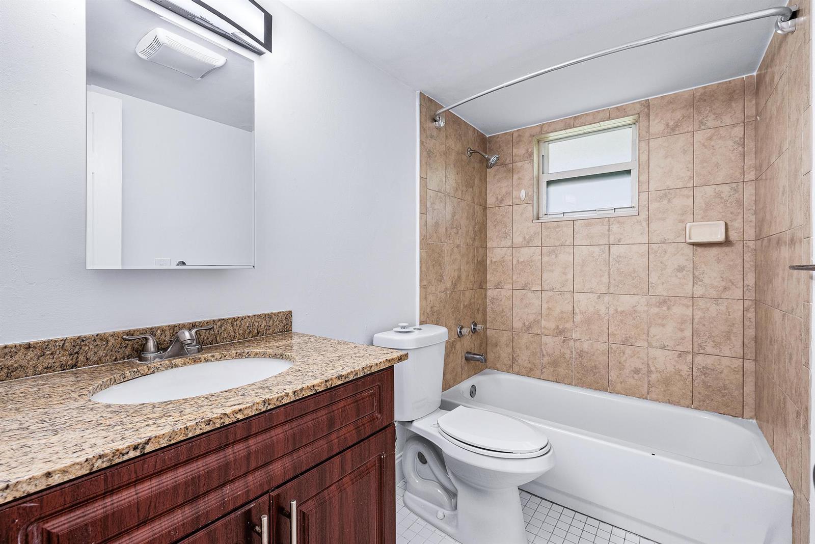 A bathroom features a granite vanity, dark wood cabinet, white toilet, and a tiled tub-shower — 242 NE 12th Street # 2, Delray Beach FL 33444, DELRAY BEACH, FL