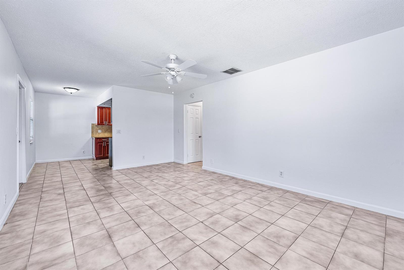An open-plan living area features white walls, tile flooring, and a ceiling fan — 242 NE 12th Street # 2, Delray Beach FL 33444, DELRAY BEACH, FL