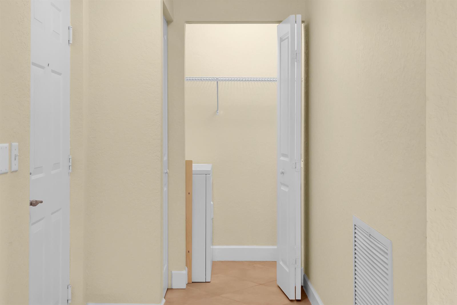 A hallway with beige walls leads to a closet containing a white appliance — 1690 Renaissance Commons Boulevard # 1212, Boynton Beach FL 33426, BOYNTON BEACH, FL