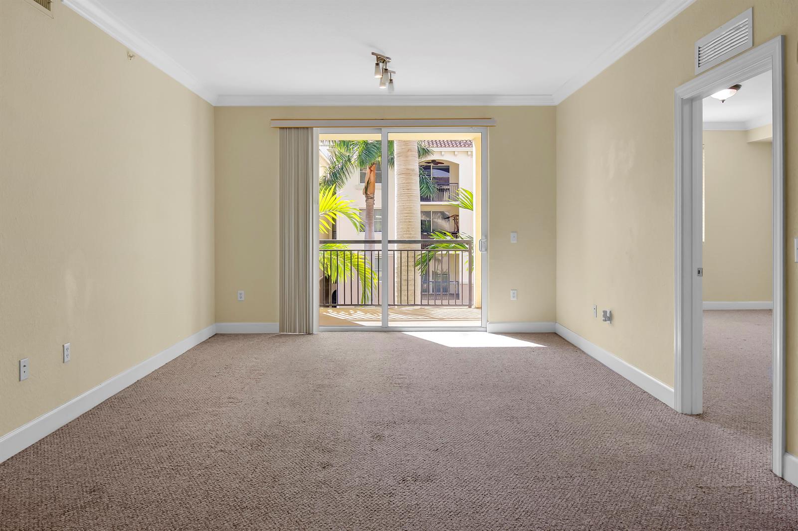 An empty bedroom with beige walls, tan carpet, and a sliding glass door to a balcony — 1690 Renaissance Commons Boulevard # 1212, Boynton Beach FL 33426, BOYNTON BEACH, FL