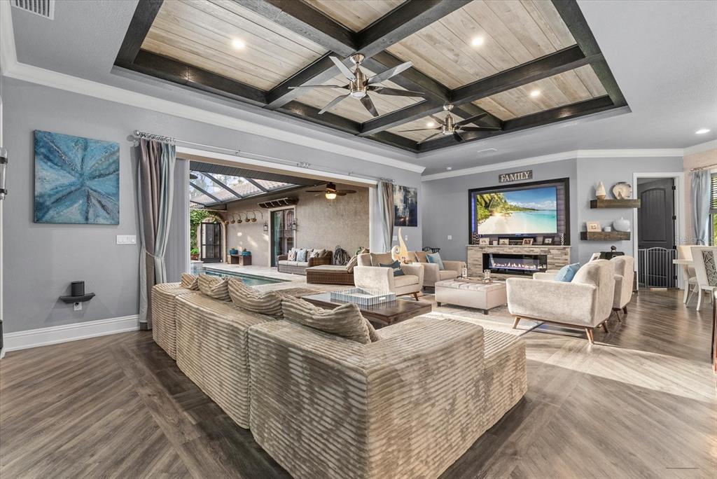 A living room with a coffered ceiling, fireplace, and large sliding doors opening to a pool — 3604 TROPICAIRE BOULEVARD, NORTH PORT, FL