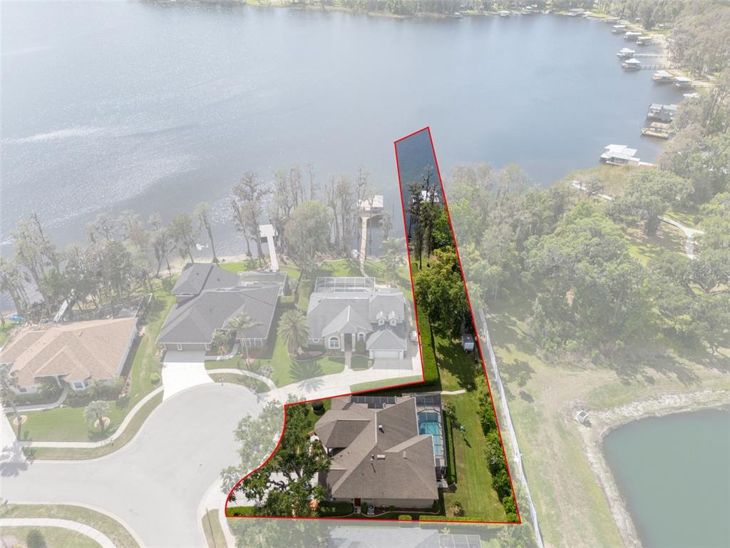 An aerial view shows a house with a pool on a lakefront lot — 21133 MARSH HAWK DRIVE, LAND O LAKES, FL