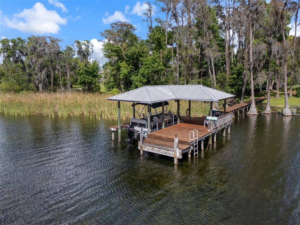 An aerial view shows a covered wooden boat dock with a pontoon boat on a lake — 21133 MARSH HAWK DRIVE, LAND O LAKES, FL