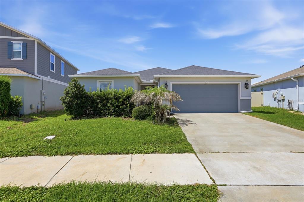 A single-story house with a gray garage, light-colored siding, and a front lawn — 232 LAKE LUCERNE WAY, WINTER HAVEN, FL