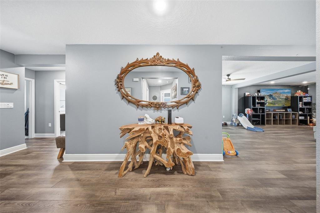 A foyer features a rustic wood console table, an ornate oval mirror, and wood-look flooring — 232 LAKE LUCERNE WAY, WINTER HAVEN, FL