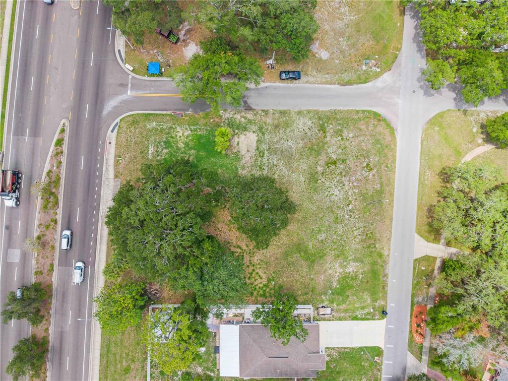An aerial view shows a vacant, grassy corner lot bordered by a road and trees — 7514 N 40TH STREET, TAMPA, FL
