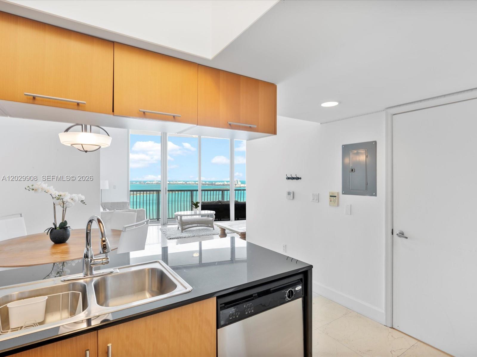 A kitchen with light wood cabinets and black countertops overlooks a balcony with ocean views — 1750 N Bayshore Dr # 5601, Miami FL 33132, MIAMI, FL