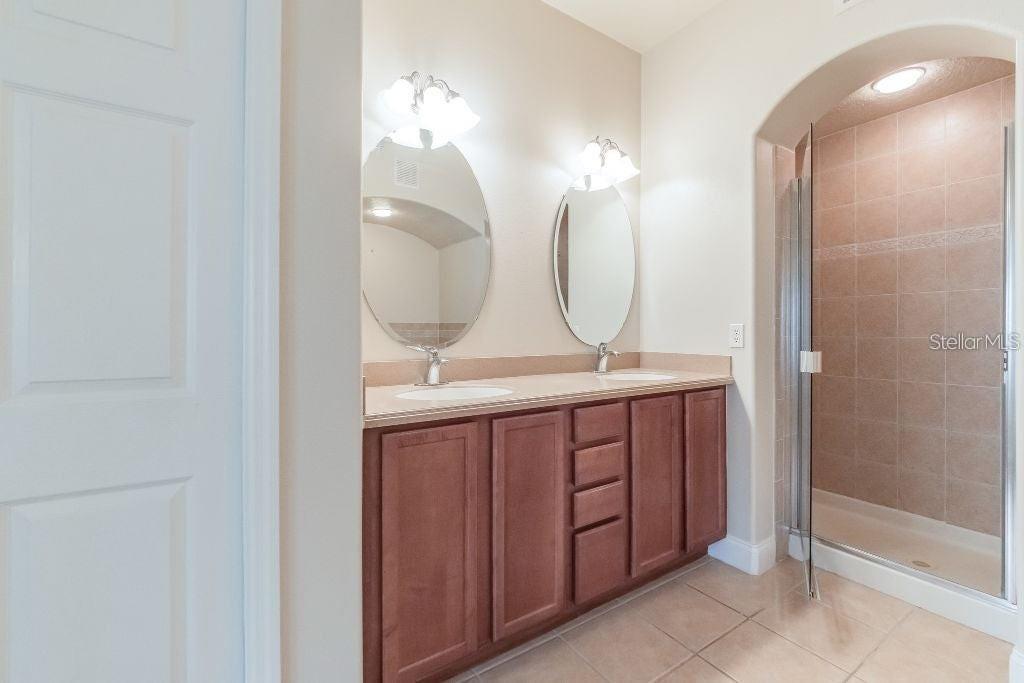 A bathroom features a double-sink vanity with wood cabinets and a glass-enclosed walk-in shower — 1733 PROSPECT AVENUE, ORLANDO, FL
