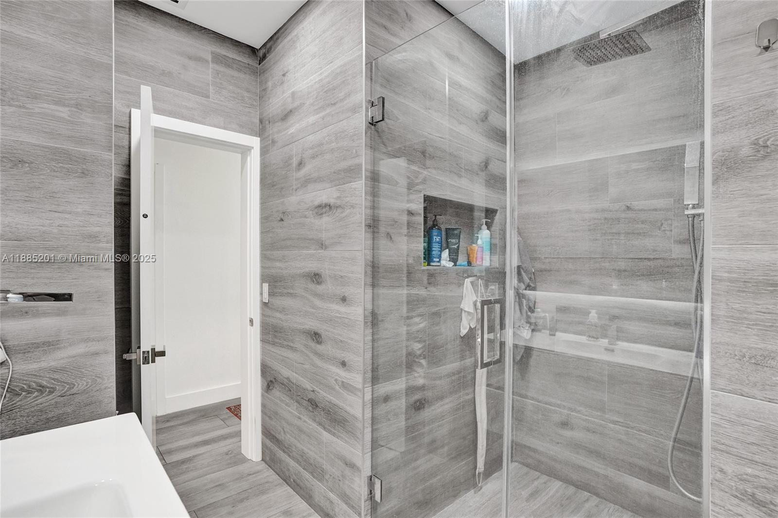 A bathroom features a glass-enclosed shower with gray wood-look tile walls and flooring — 3784 Sheridan Ave, Miami Beach FL 33140, MIAMI BEACH, FL