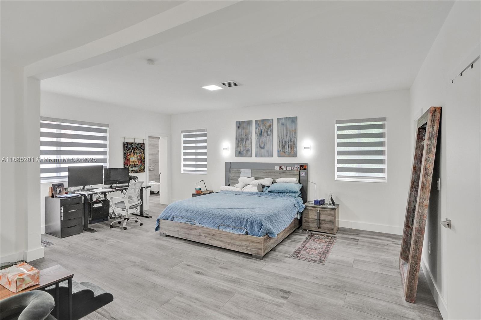 A bedroom features a bed, a desk setup, light wood-look flooring, and three wall-mounted artworks — 3784 Sheridan Ave, Miami Beach FL 33140, MIAMI BEACH, FL