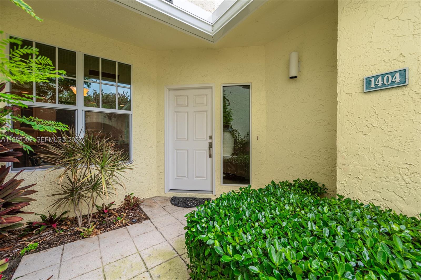 The exterior entrance features a white door, a side window, and a house number sign — 1404 Mainsail Cir # 1404, Jupiter FL 33477, JUPITER, FL