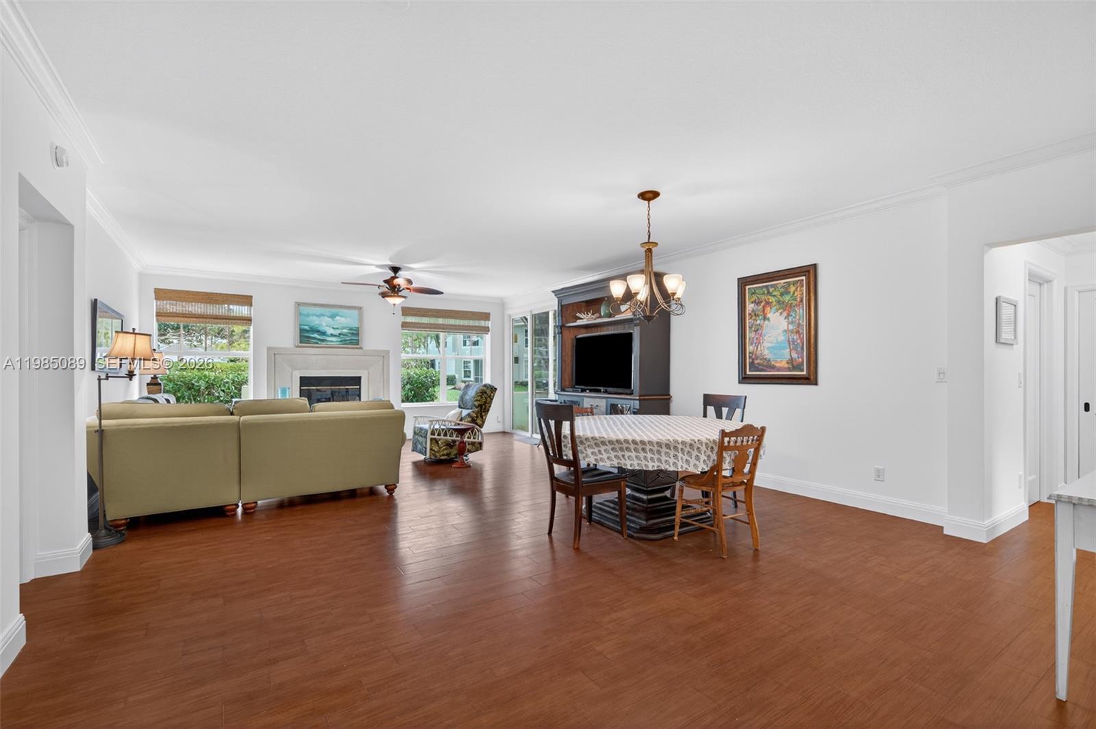 A spacious living and dining area features hardwood floors, a fireplace, and a ceiling fan — 1404 Mainsail Cir # 1404, Jupiter FL 33477, JUPITER, FL