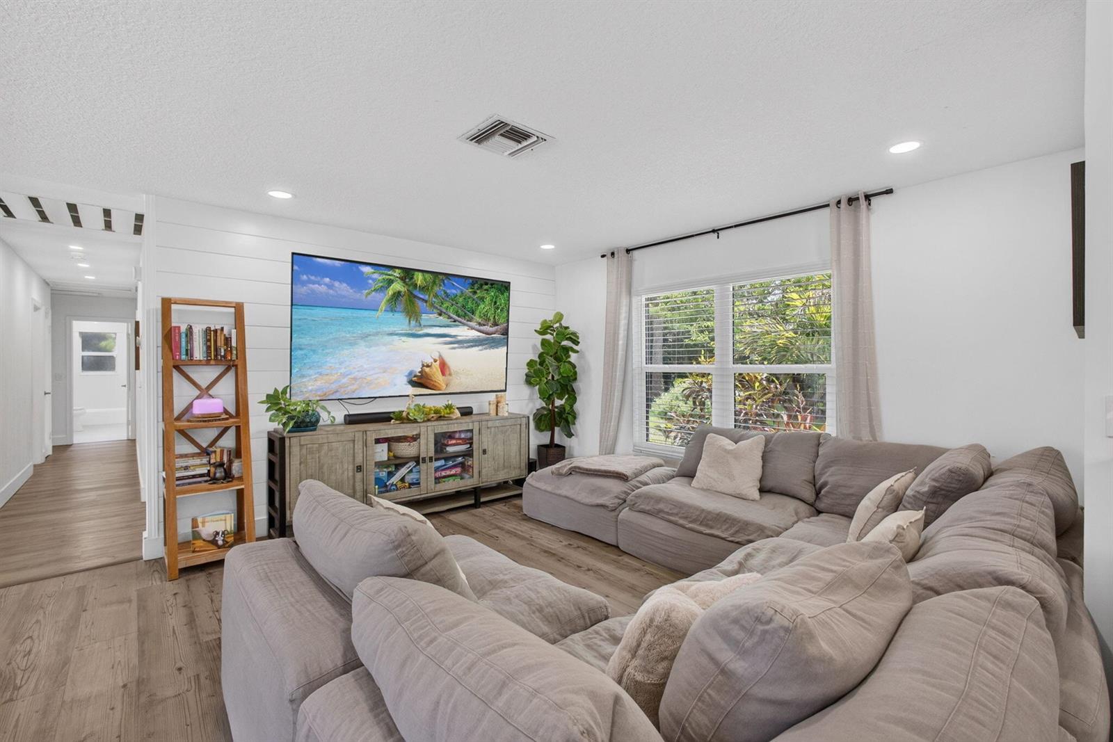 A living room features a large sectional sofa, a wall-mounted television, and wood-look flooring — 17968 Bridle Court, FL 33478, FL