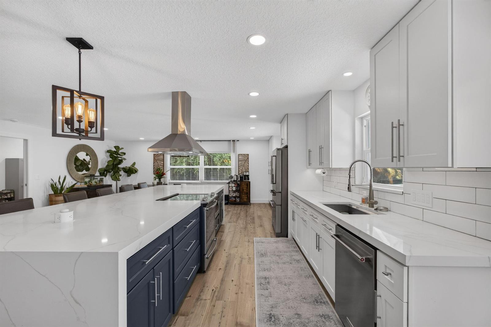 A modern kitchen features a large blue island with a waterfall countertop and white cabinets — 17968 Bridle Court, FL 33478, FL