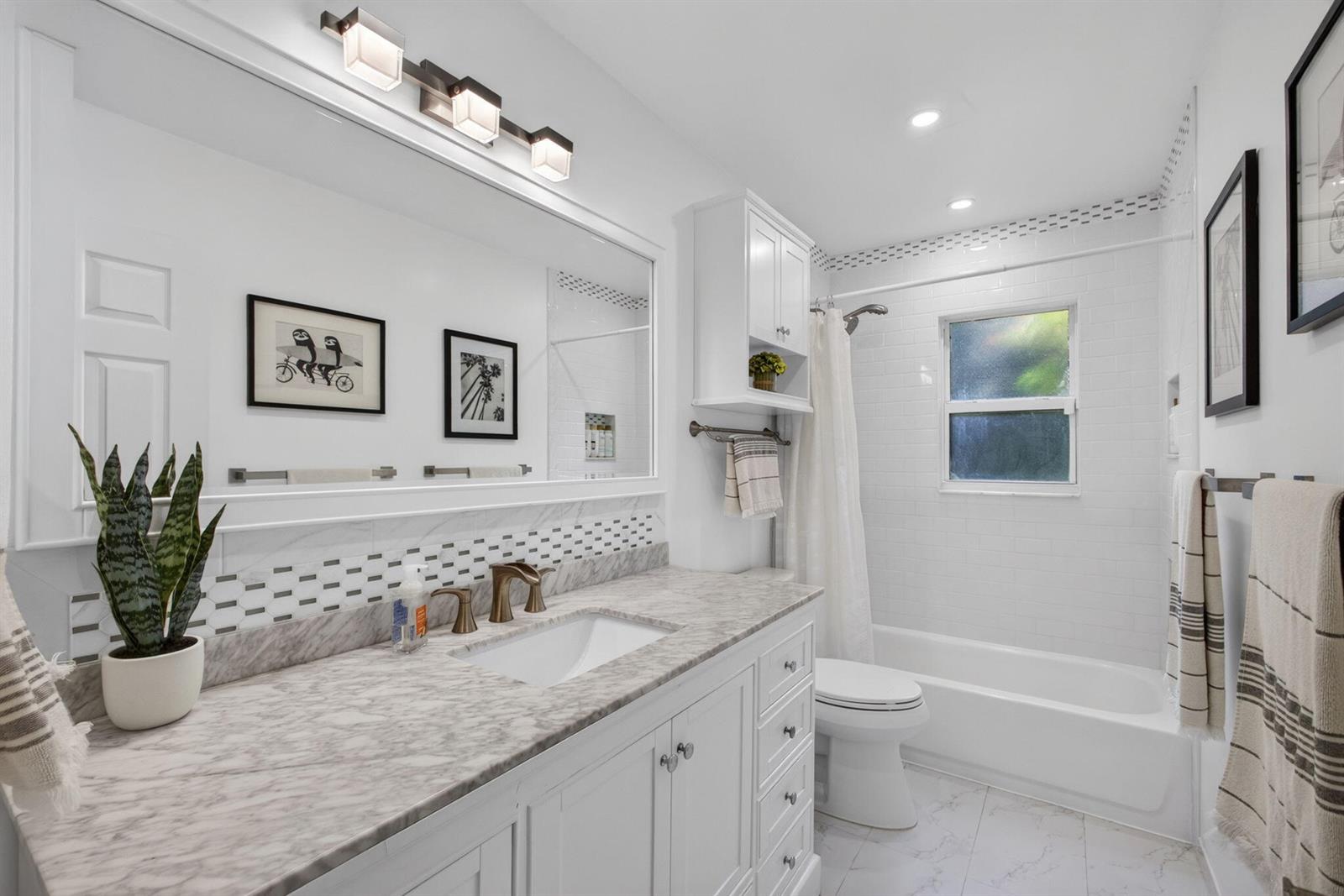 A white bathroom features a marble vanity, a bathtub with a shower, and subway tile — 17968 Bridle Court, FL 33478, FL