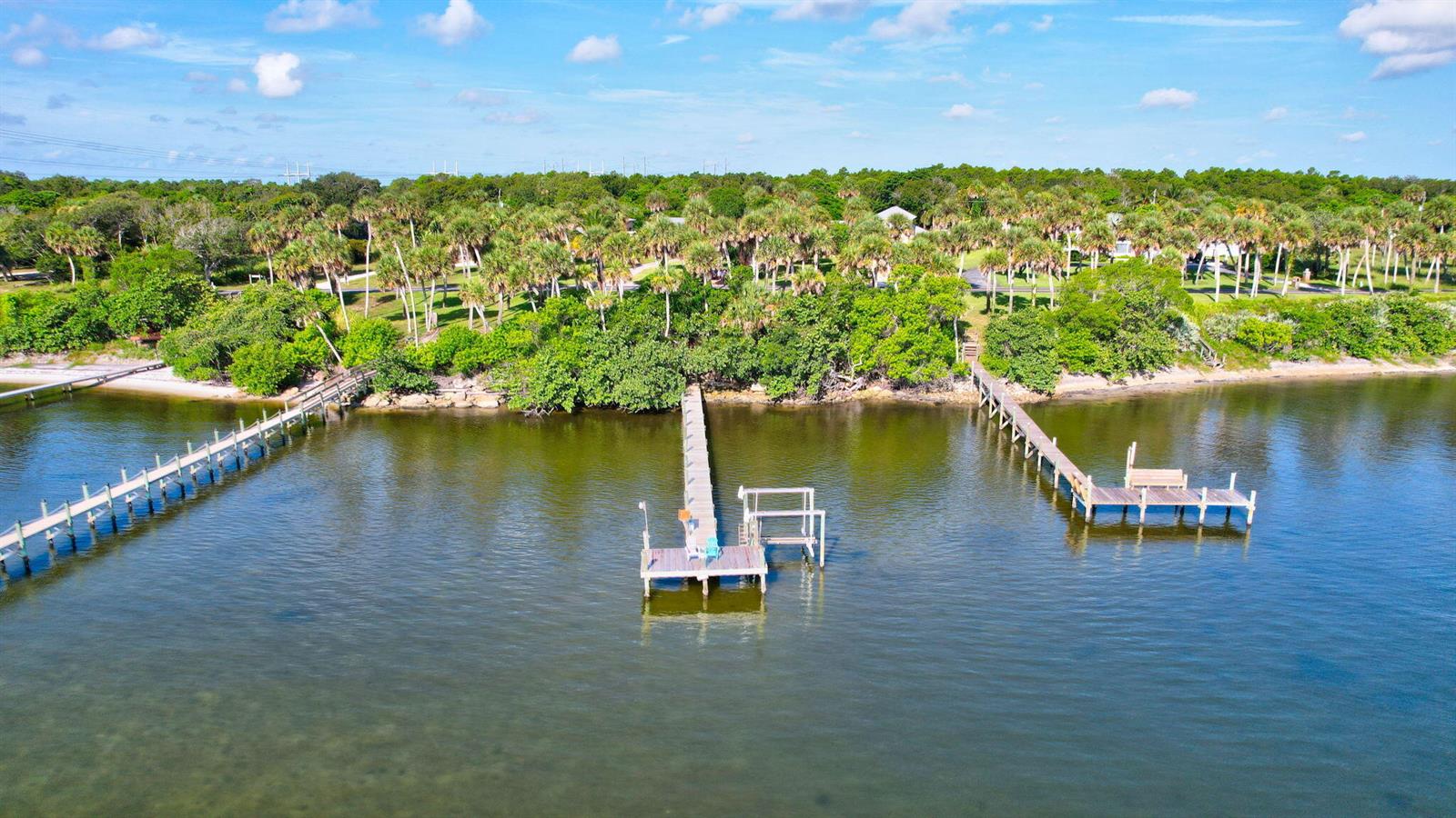 An aerial view shows three wooden docks extending into a calm body of water — 7501 S Indian River Drive, Fort Pierce FL 34982, FORT PIERCE, FL
