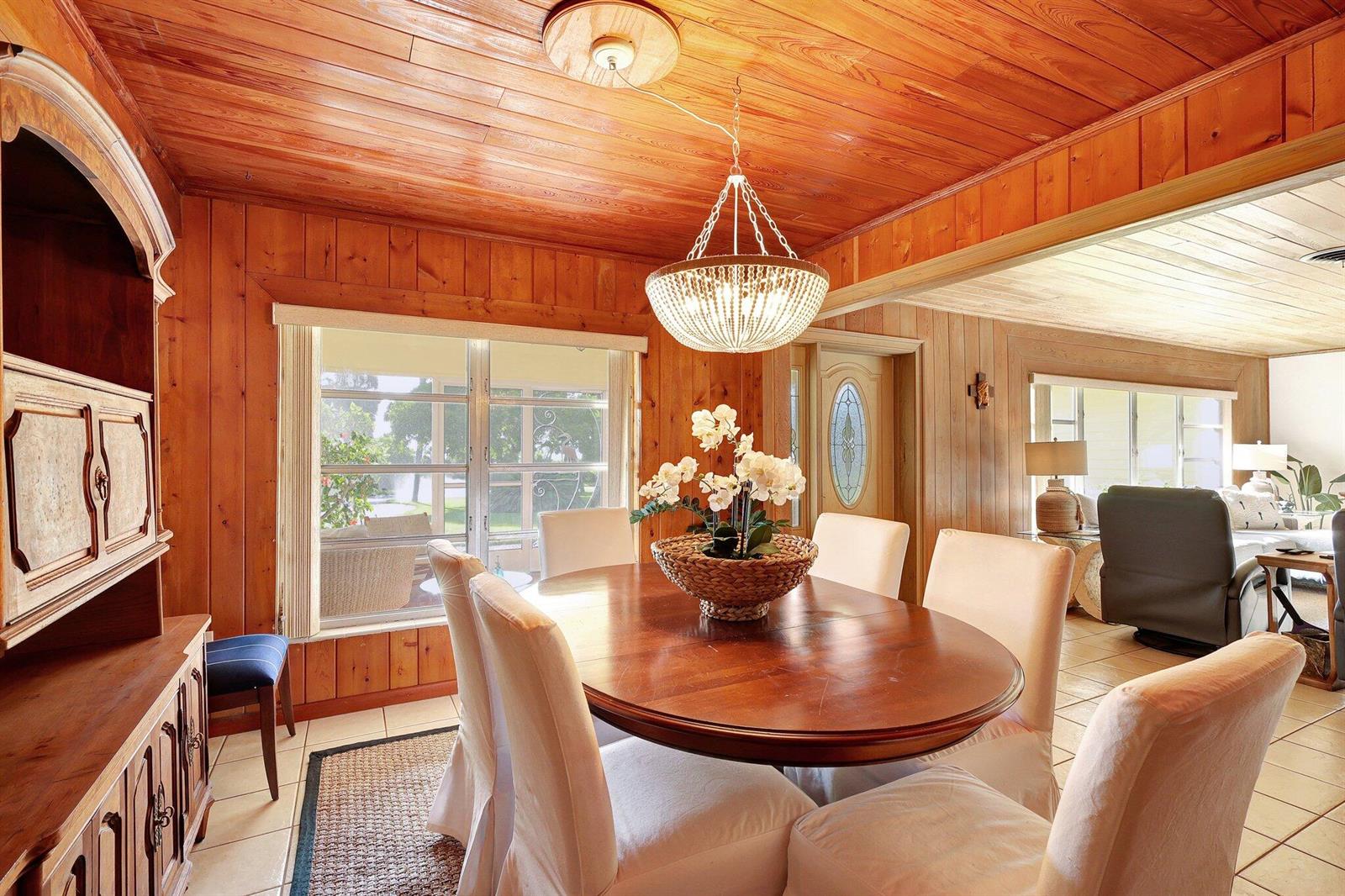 A dining room with wood-paneled walls and ceiling, a chandelier, and a wooden table — 7501 S Indian River Drive, Fort Pierce FL 34982, FORT PIERCE, FL