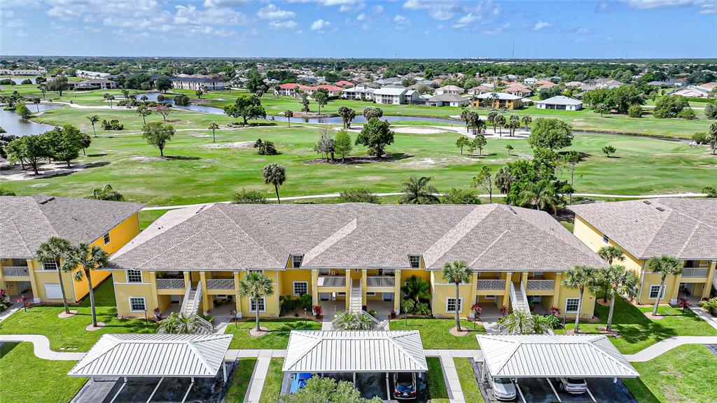 An aerial view of a multi-story yellow apartment building with covered parking and golf course — 1295 SAXONY CIRCLE UNIT 2103, PUNTA GORDA, FL