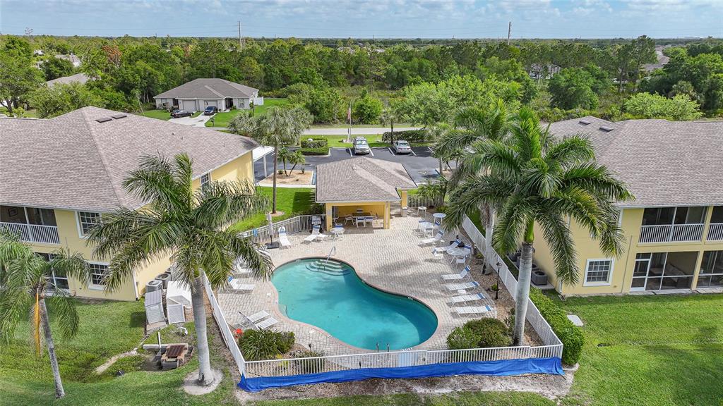 An aerial view of a community swimming pool surrounded by palm trees and apartment buildings — 1295 SAXONY CIRCLE UNIT 2103, PUNTA GORDA, FL