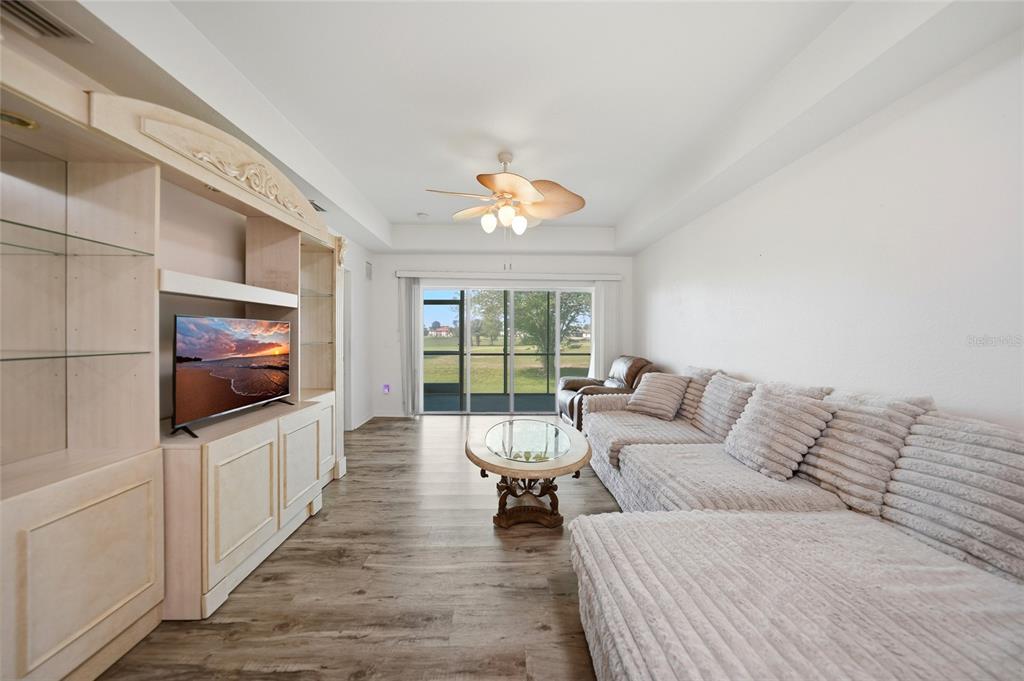A living room features a large sectional sofa, a media center, and sliding glass doors — 1295 SAXONY CIRCLE UNIT 2103, PUNTA GORDA, FL