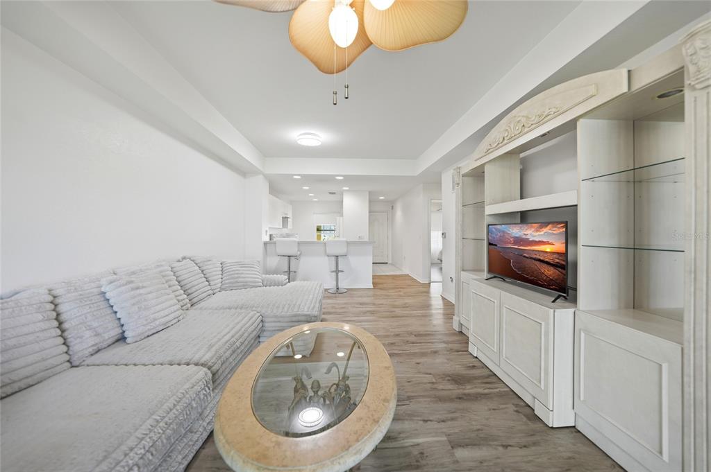A living room features a sectional sofa, a glass-topped coffee table, and a white entertainment center — 1295 SAXONY CIRCLE UNIT 2103, PUNTA GORDA, FL