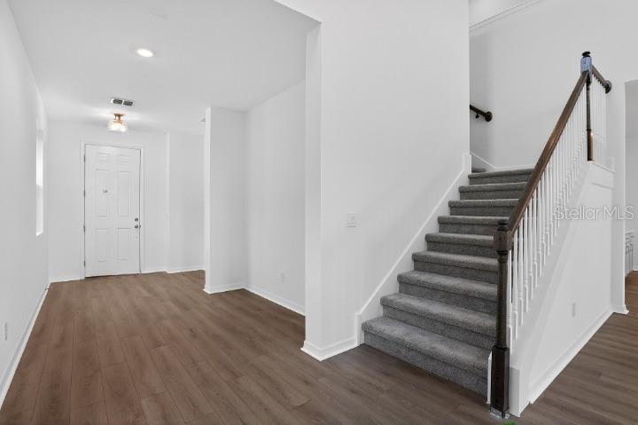 An entryway features wood-look flooring, a carpeted staircase with a wooden handrail, and a door — 17631 LAKE STAR ROAD, WINTER GARDEN, FL