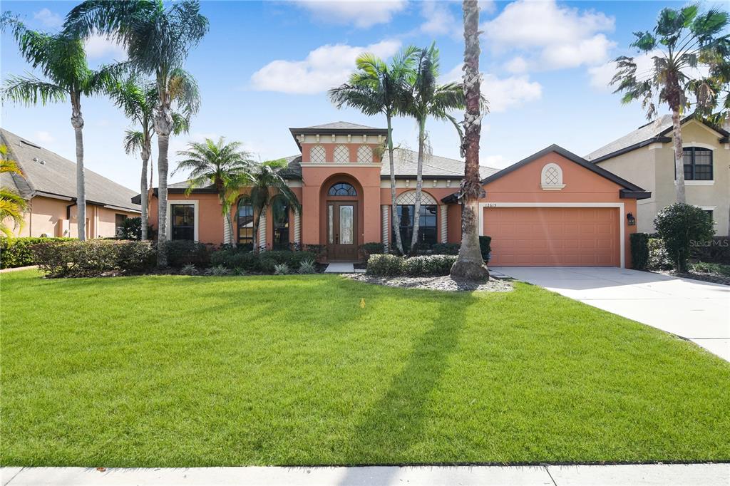 A single-story peach-colored house with a two-car garage and palm trees in the front yard — 12615 20TH STREET E, PARRISH, FL
