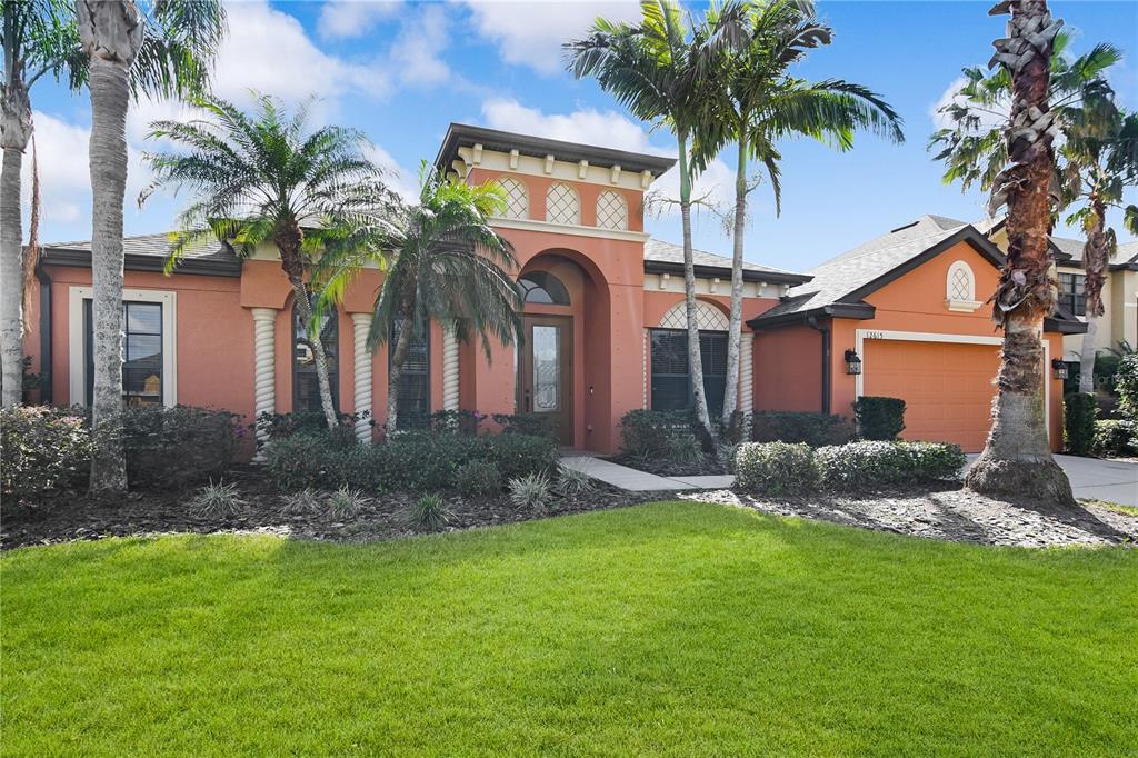 A single-story house with an orange stucco exterior, a front porch, and palm trees — 12615 20TH STREET E, PARRISH, FL