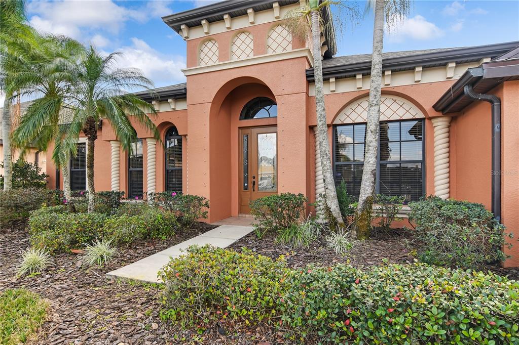 The exterior of a peach-colored house features a central arched entryway and decorative lattice windows — 12615 20TH STREET E, PARRISH, FL