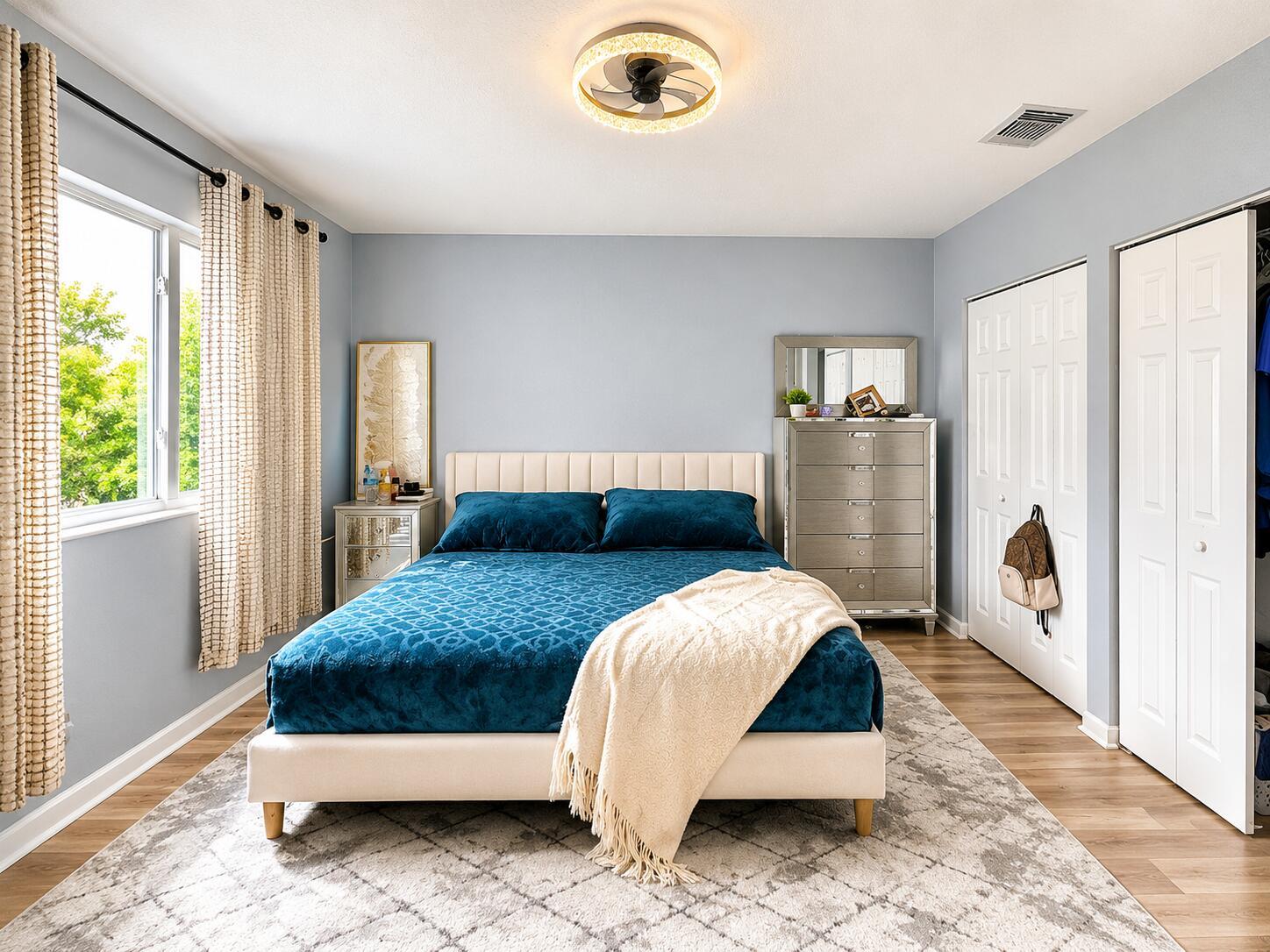 A bedroom features a bed with blue bedding, a mirrored dresser, and a ceiling fan — 2228 Oakmont Drive, Riviera Beach FL 33404, RIVIERA BEACH, FL