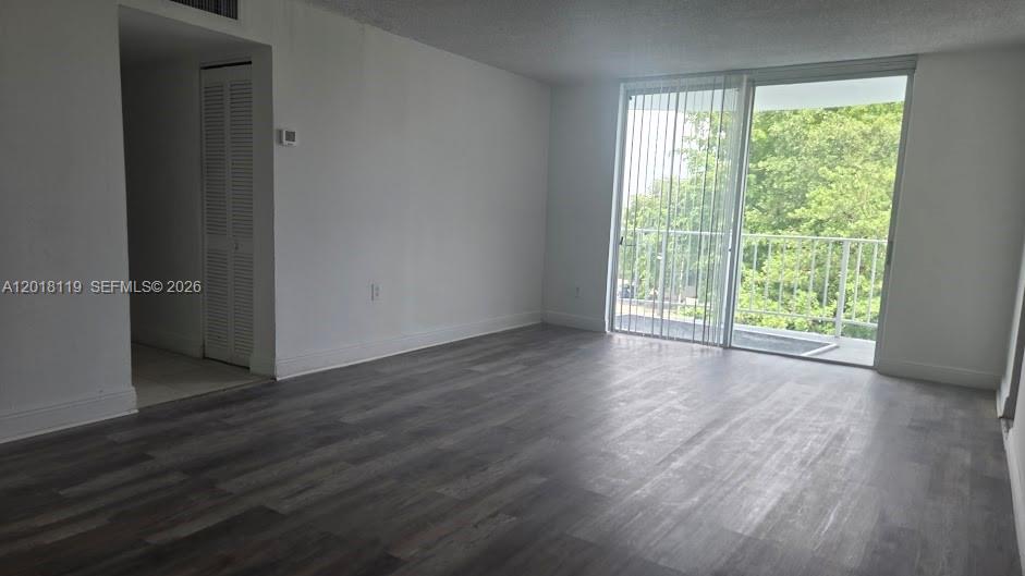 An empty living room features gray wood-look flooring, white walls, and a sliding glass door — 492 NW 165 St Rd # C516, Miami FL 33169, MIAMI, FL
