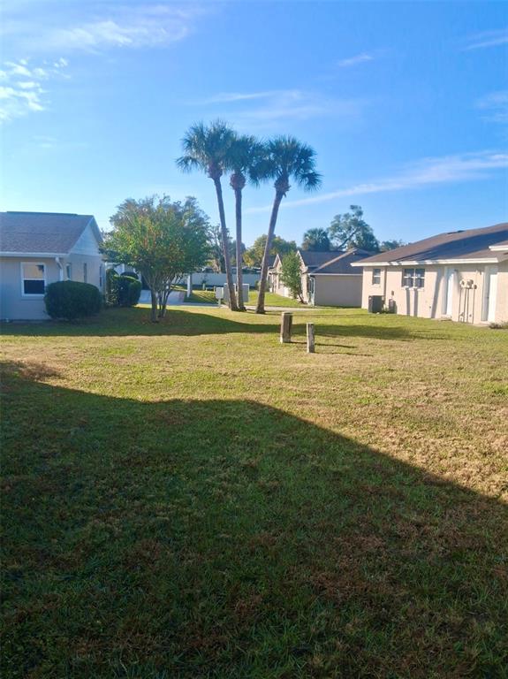 A single-story duplex with a tan exterior, a covered carport, and a green lawn — 225 PINE BLUFF AVENUE UNIT 560, DELAND, FL