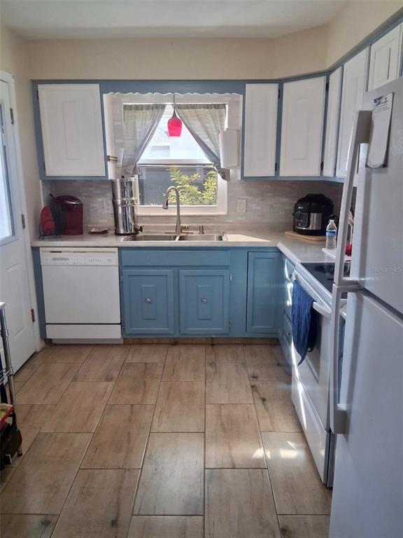 A single-story house features a tan exterior, green shutters, a covered carport, and a driveway — 225 PINE BLUFF AVENUE UNIT 560, DELAND, FL