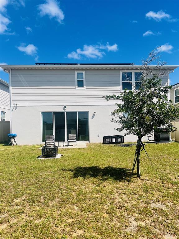 The exterior of a two-story house features light-colored siding, a sliding glass door, and backyard — 1120 SUGARWOOD STREET, DAVENPORT, FL