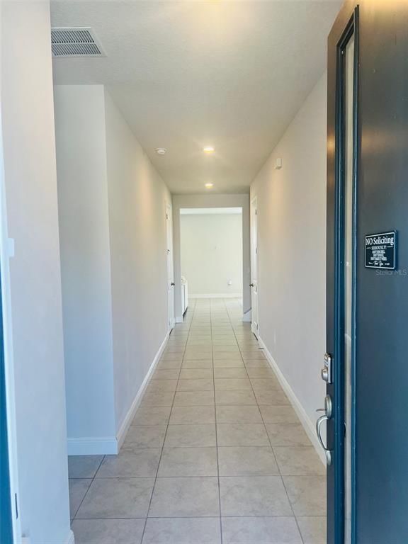 A long hallway with light-colored tile flooring leads toward an open doorway — 1120 SUGARWOOD STREET, DAVENPORT, FL