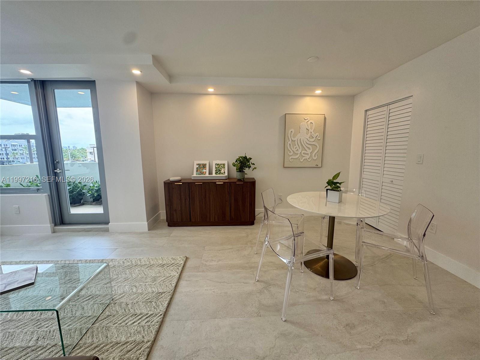 A dining area features a round table, clear chairs, a wooden sideboard, and tile flooring — 2899 Collins Ave # 424, Miami Beach FL 33140, MIAMI BEACH, FL