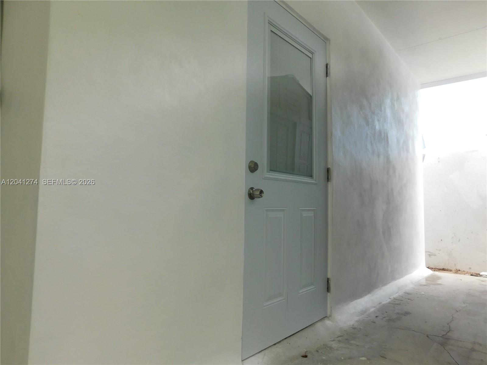 A white door with a glass panel is set into a plain white wall — 2230 NW 58th St # B, Miami FL 33142, MIAMI, FL